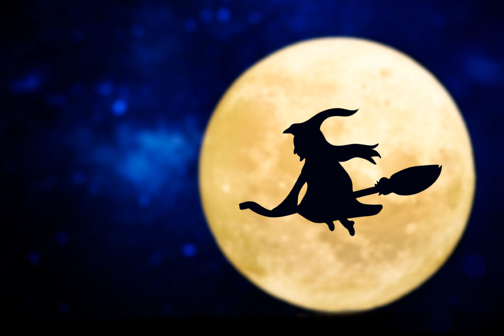 Witch on broomstick flying across full moon